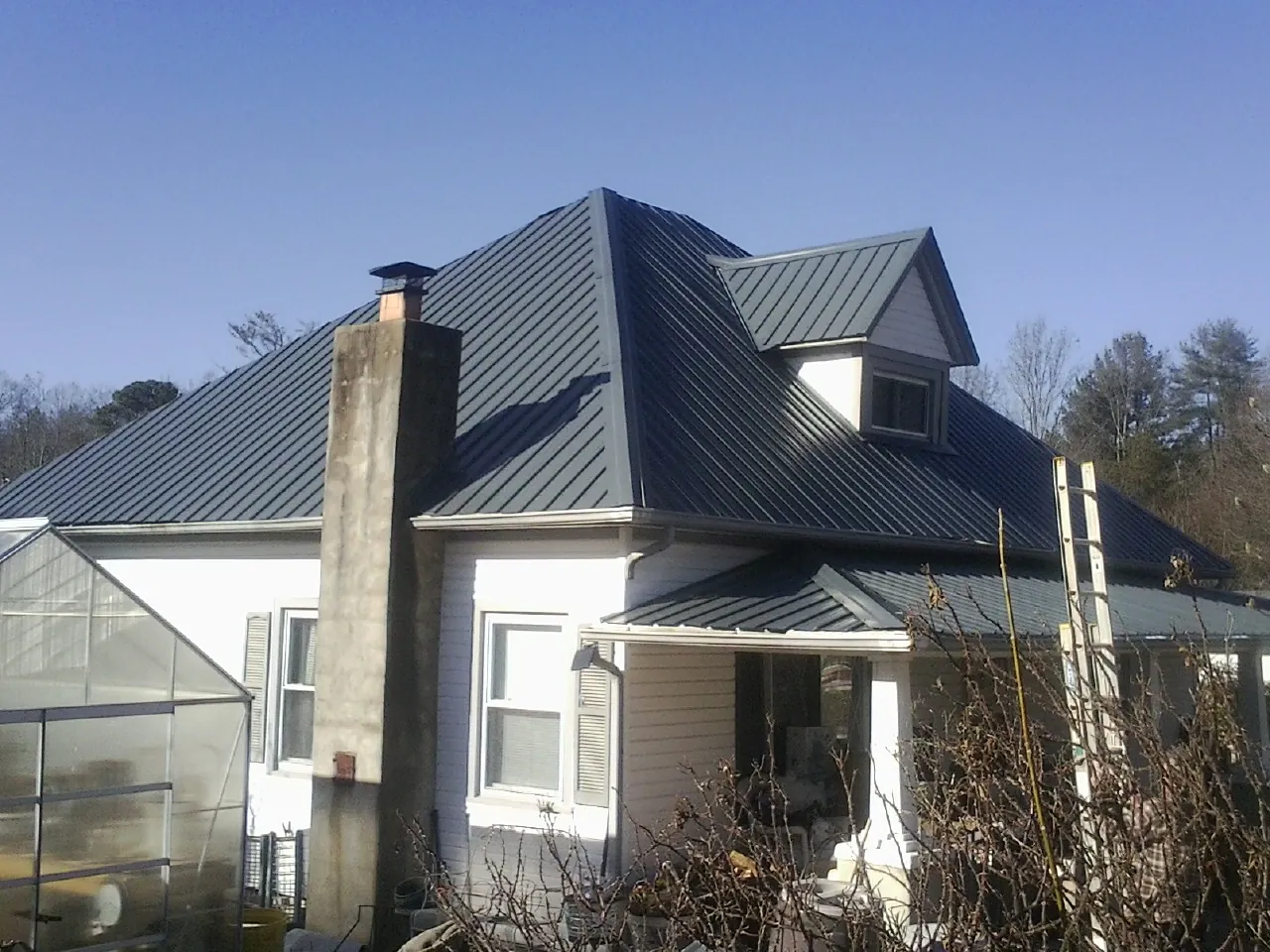 Dark blue standing seam metal roof on a white farmhouse with dormer — Slate & Tile Roof Repair by Roofing Brothers in Doylesburg