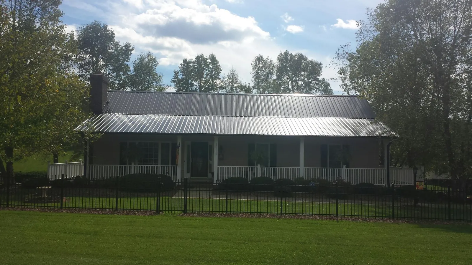 Gray metal roof on a brick ranch with a full width front porch — Gutter Guard Installation work by our crew in Doylesburg