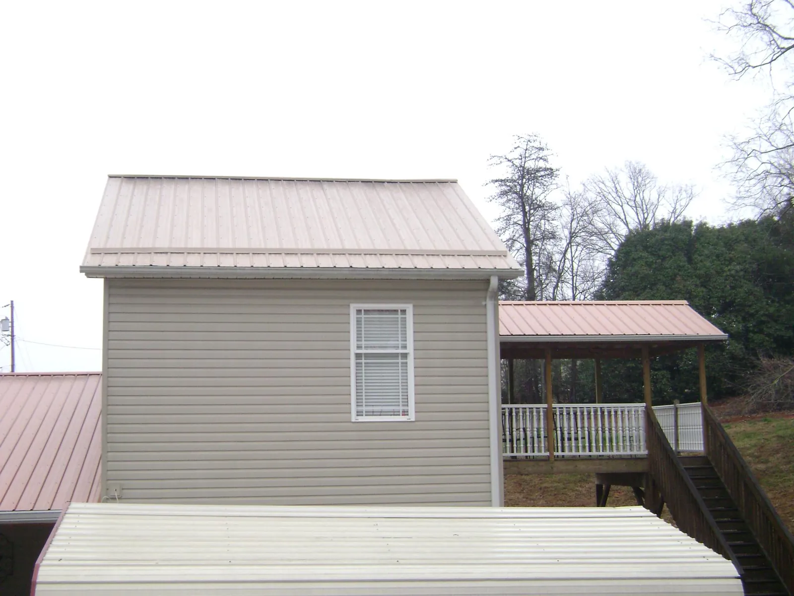 Tan metal roofs on a two story addition and attached porch, from a Roof Replacement job in Doylesburg