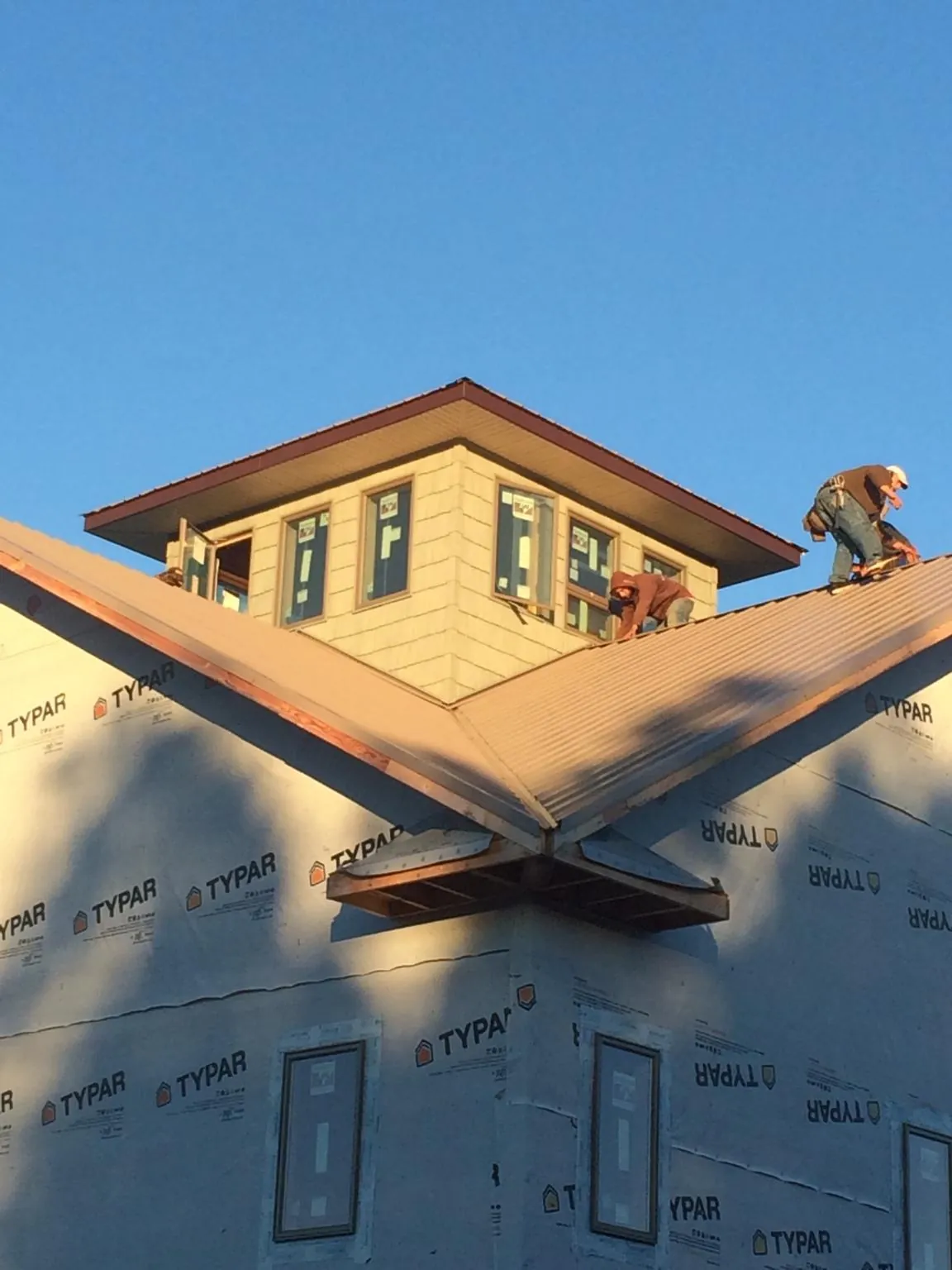 Roofers working around a rooftop cupola on a new metal roof at sunset — Roof Waterproofing in Doylesburg by Roofing Brothers